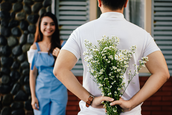 Mann versteckt Blumen für sein Date hinter seinem Rücken