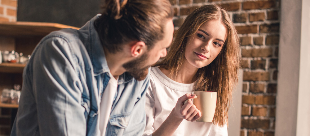 Pärchen sitzt in der Küche und trinkt Kaffee